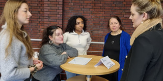 Vier Studentinnen tauschen sich an einem Stehtisch auf dem Kontakttag aus. 