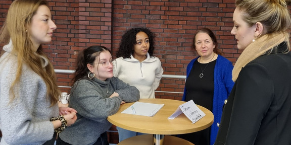 Vier Studentinnen tauschen sich an einem Stehtisch auf dem Kontakttag aus. 